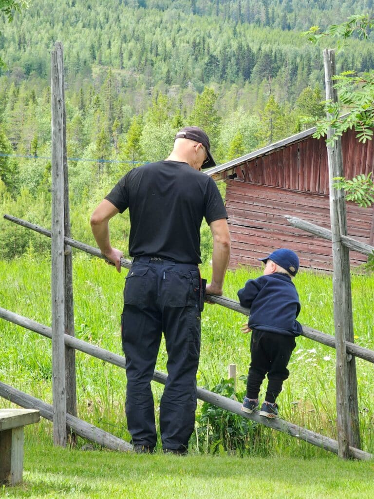 Malå_Samtal vid hagen fotograf Linda Sandqvist Stor och liten man som står vid en hage.