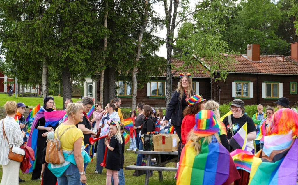 Prideflaggor och människor i färgglada kläder. 